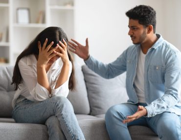Young Indian couple experiences moment of tension, woman covering her face and man expressing concern, showcasing emotional challenges in relationships